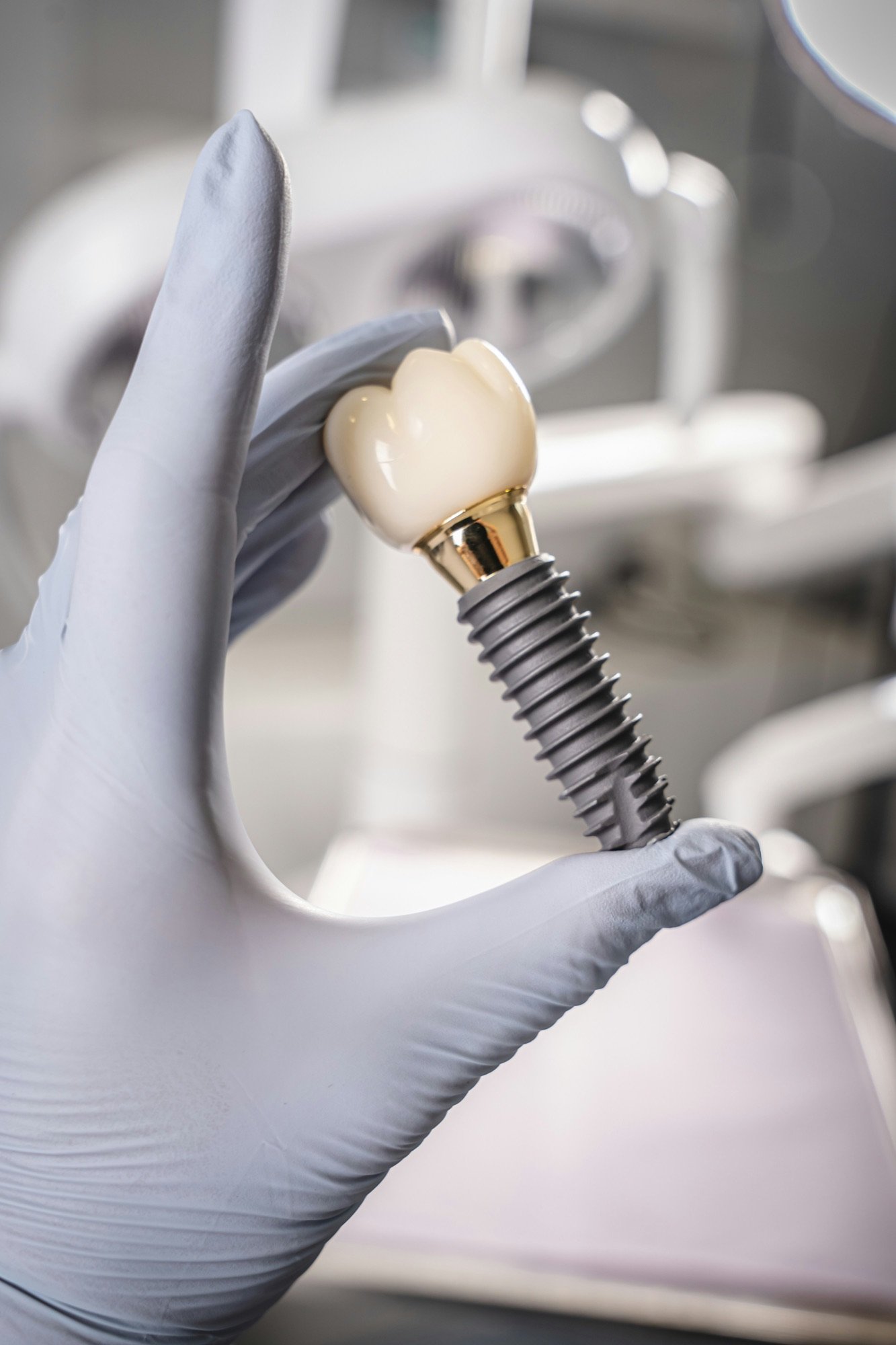 Dental implant with crown held by a gloved hand